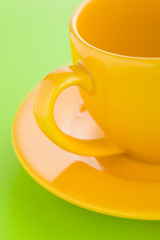 Empty yellow coffee cup over a light green background