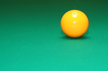 Close-up shot of pool table and yellow ball.