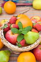 a wooden basket withfresh fruits and green mint leaves
