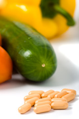 closeup pills with vegetables pepper tomato and cucumber