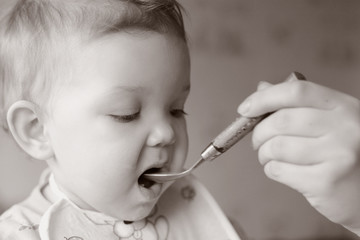 Baby in the kitchen. The mother is feeding her baby.