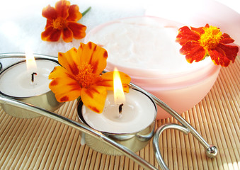 cosmetic moisturizing cream and candle with flowers