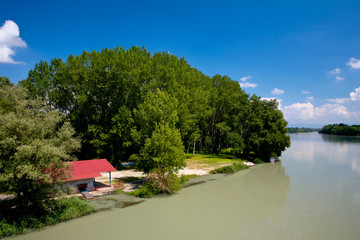Maison rouge dans une foret au bord d'un fleuve