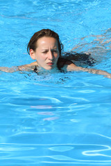 Fototapeta na wymiar Frau schwimmt im Freibad in der Sonne