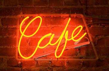 a neon sign on a brick wall outside of a cafe