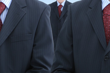 Three male trunks in dark suits with red neckties