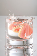artificial Teeth splashing on water glass