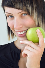 The young beautiful girl holds a green apple in a hand