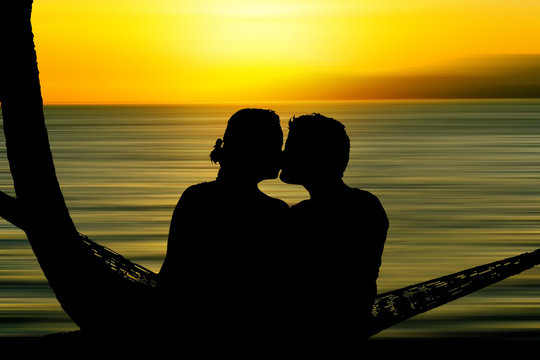 Kissing couple at sunset silhouette.