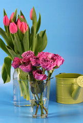 Bunches of pink roses and tulips with a green watering can
