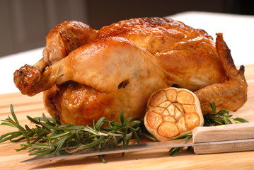 Whole roasted chicken with garlic, rosemary and carving knife