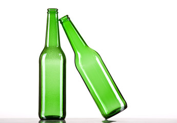 Green beer bottle falling on another one. White background.