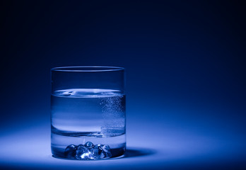 Glass of mineral water with dissolving pill. Blue. Shallow DOF..
