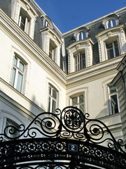 Hôtel particulier. Coin de façade blanche au dessus d'une porte en fer forgée.