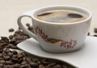 Cup of coffee and grains over sackcloth