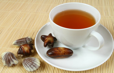 Tea cup and  chocolates . Hot drink.