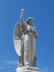 Detail of winged angel statue against blue sky