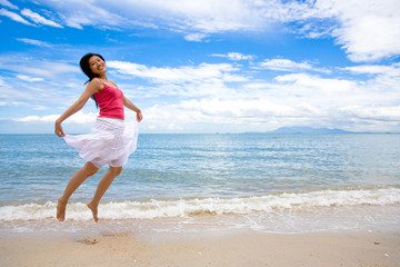 happy young woman jumping on the beach