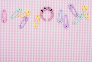 Baby bracelet with safety pins om a pink and white background