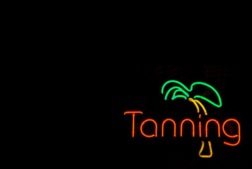 A colorful neon sign advertising a tanning booth.