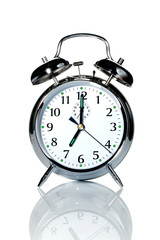 A chrome alarm clock with the hands at 7 o'clock.