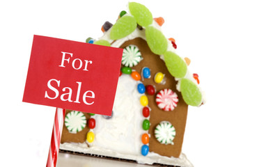 A 'For Sale' sign in front of a gingerbread house.