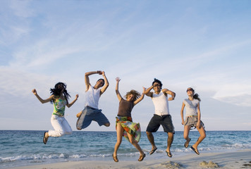 Group of five friends jumping on the beach