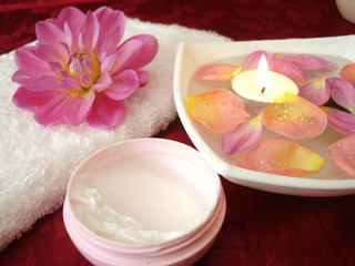 Obraz na płótnie Canvas spa essentials (cream, towel and candle with flowers)
