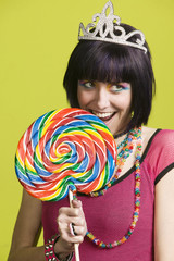 Pretty young woman takes a bite from a large lollipop