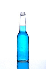 bottle with blue liquid on wet reflective surface on white