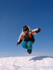 Fototapeta na wymiar Boy jumping over snow on blue sky.