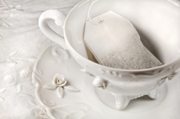 Tea bag in a white antique cup and saucer.