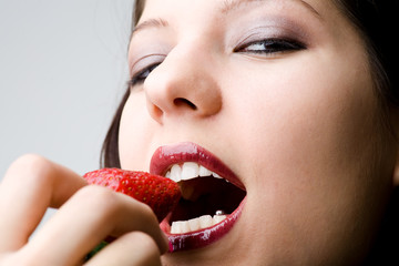 Roter Mund von Frau mit Erdbeere in den Fingern