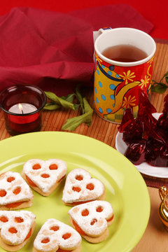 Cookies on green plate with candle and a cup of tea
