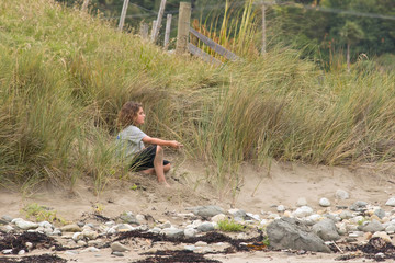 A young caucasian male sits on a sand dune
