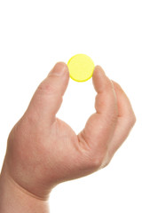 Human hand holding big yellow pill