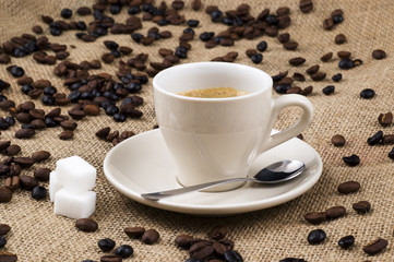 White cup of coffee on beans and sack background