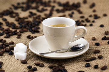 Cup of coffee, beans and sack background, shallow depth of field