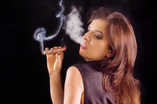 Young beautiful woman blowing smoke rings from cigar