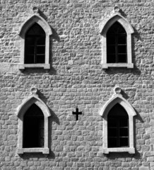 Brick wall with gothic windows and cross. B&W image.