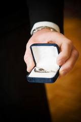wedding rings held in grooms hand