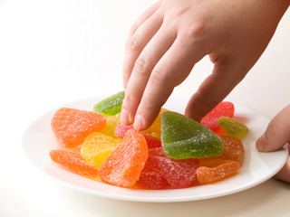 Woman's hands holding the plate full of sweet marmalade pieces