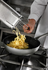 Chef preparing pasta on professional kitchen in restaurant