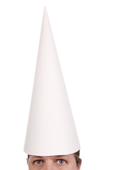 Woman in a dunce cap with eyes open over a white background