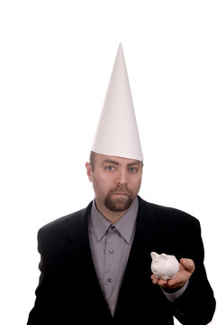 Man in a dunce cap with a piggybank over a white background