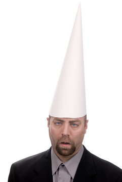 Man in a dunce cap with eyes crossed over a white background