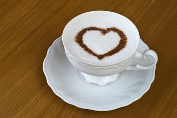 Coffee cup with cinnamon heart shape on wooden table