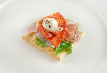 Ham tomato lettuce and mayo on a cracker snack.
