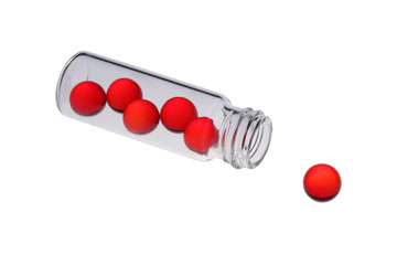Red pills in a vial and and near to it. Isolated on white.