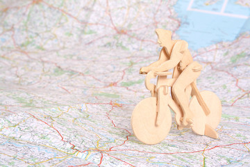 Wooden model of bicyclist on background of map